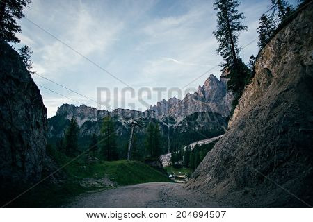 View on quiet and empty skiing slopes and ski lifts high on altitude in mountains during off season in summer gravel road in between leading to parking lot