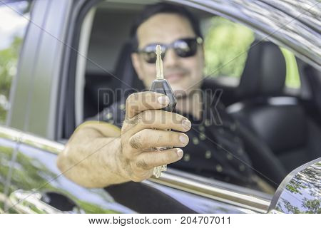 Asian casual man show car key while sitting in carcar park in outdoor garden
