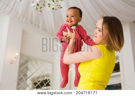 happy family. Mother throws up baby, playing at home.