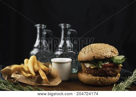Craft beef burger and french fries on wooden table on dark blue background.