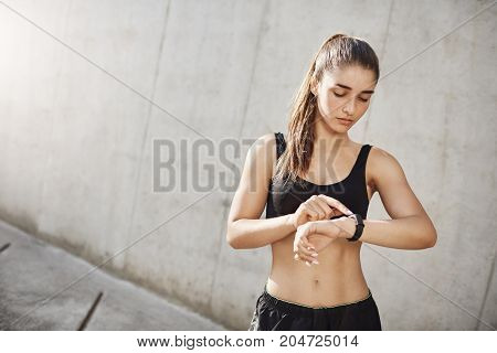 Young female runner using a fitness tracker to know her heartrate. Science on the service of sport.