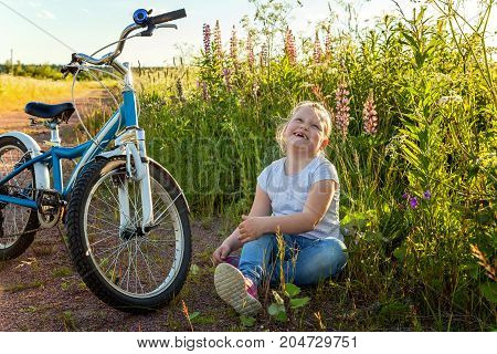 Beautiful smiling girl issitting near the bicycle in the park