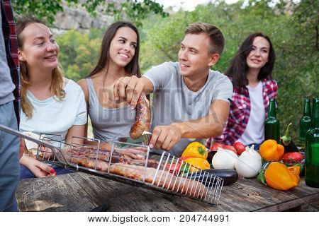 Romantic picnic. Group adult friends enjoying a healthy outdoor meal sitting together at a table in a lush green garden laughing and joking. Friends Outdoors Nature Picnic Chilling Out Unity Concept.