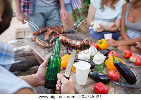 Romantic picnic. Group adult friends enjoying a healthy outdoor meal sitting together at a table in a lush green garden laughing and joking. Friends Outdoors Nature Picnic Chilling Out Unity Concept.