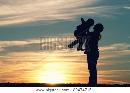 a mother with her child embracing at sunset.