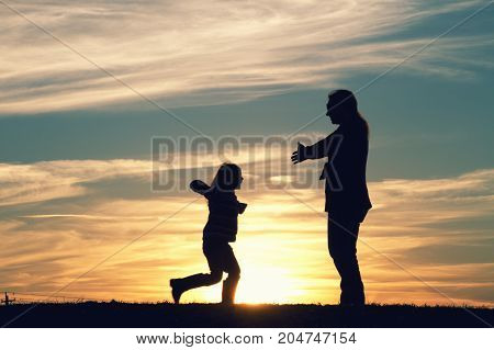 a mother with her child embracing at sunset.