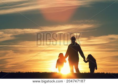 a mother walking with her children at sunset.