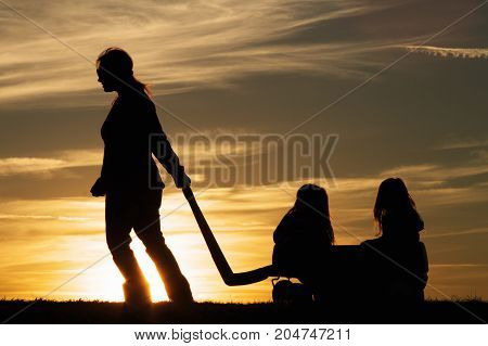a mother pulling her children in a wagon at sunset