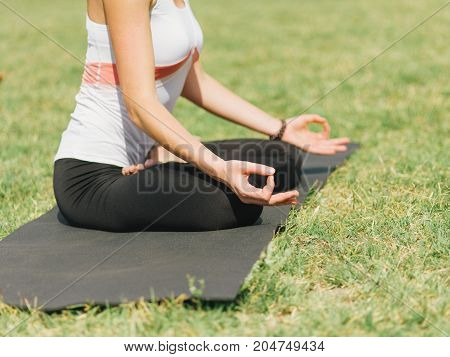 Close-up image of body parts girl's meditation at the health club outside with personal trainer, learning the correct form.