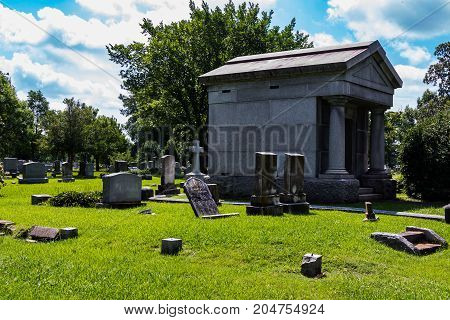 Mausoleum in a graveyard with scattered headstones.