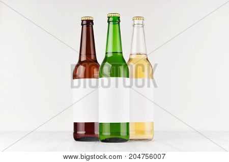 Beer bottles 500ml different colors with blank white label on white wooden board mock up. Template for advertising design branding identity.