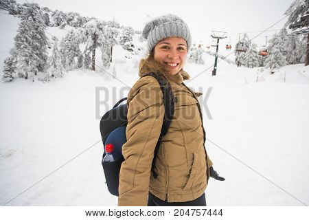 Woman winter hiking. Beautiful young caucasian woman enjoying snow dressed in a cheerful winter cap and with a satchel on her back with copyspace