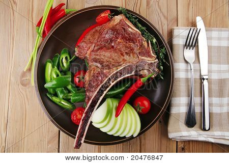 cibo di carne: arrosto nervatura sul piatto scuro con pepe timo e pomodoro sul tavolo di legno