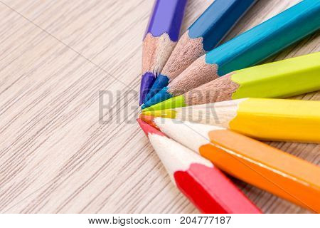 Different colored pencils photo with space for text. Seven pencils of rainbow colors lie on the table. Copyspace. Back to school. Wooden background.