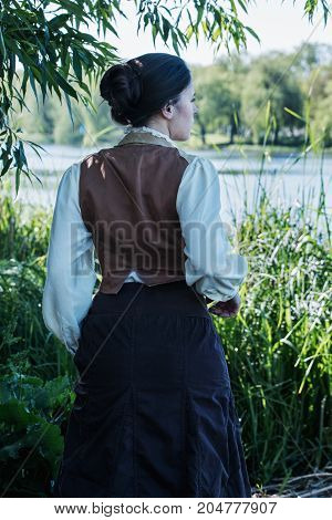 Woman in vintage clothes on the river bank