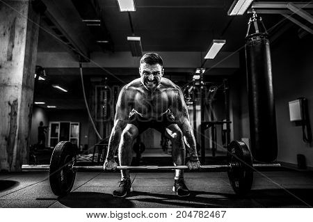 Muscular fitness man doing deadlift a barbell over his head in modern fitness center. Functional training. Snatch exercise