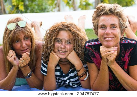 Close-up of two adult women with a preteen girl in funny posture and playing in a garden