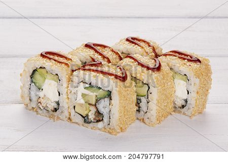 Set of eight rolls with eel sesame avocado and philadelphia cheese decorated with wasabi and ginger on a wooden white background Sushi and chopsticks