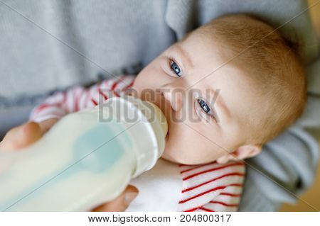 Father feeding newborn baby daughter with milk in nursing bottle. Formula drink for babies. New born child, little girl laying in bed. Family, new life, childhood, beginning, bottle-feeding concept.