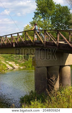 Bridge over the Dyje river in the Czech Republic. There is a cyclist on the bridge. In the river reflects the trees that grow on the banks.