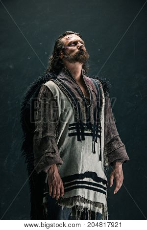 Actor in makeup, a poor man on black studio background. The bum in canvas rags. concept of vagrancy and survival