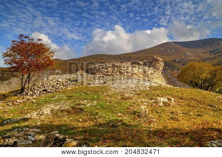 Beautiful mountain landscape with ruins of ancient fortress and colorful autumn trees