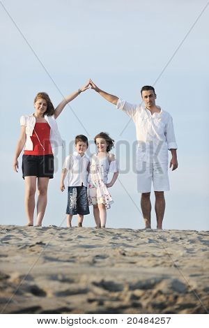 happy young family have fun on beachand showing home sign with conncected hands while protecting childrens