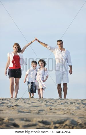 happy young family have fun on beachand showing home sign with conncected hands while protecting childrens