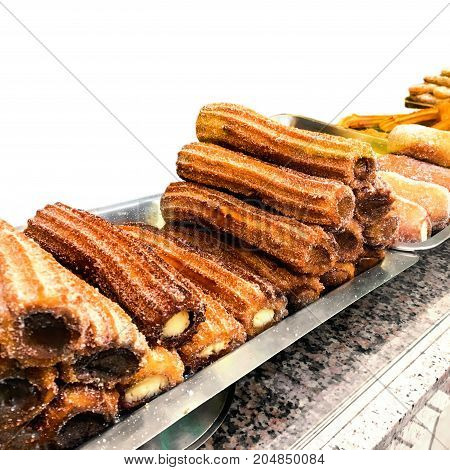 Churros on a market stall in a bakery shop. Sweet Famous Spanish dessert with chocolate sauce close up