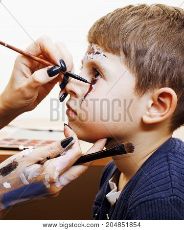 little cute child making facepaint on birthday party, zombie Apocalypse facepainting, halloween preparing concept, lifestyle people close up