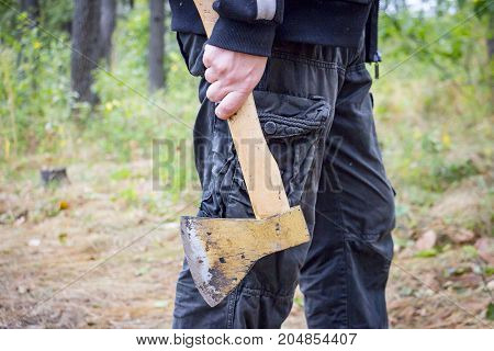 A man holds an ax in his hand while in the forest