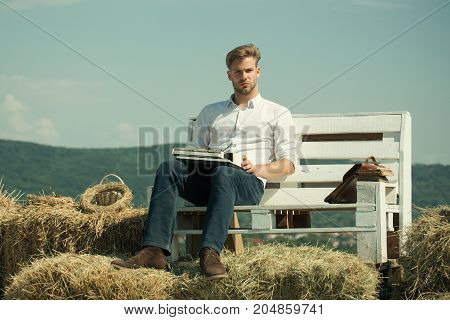 Secretary or assistant typing on typewriter on blue sky. Man sitting on bench on natural landscape. Macho working on sunny day. Vintage equipment and archaism. Summer vacation concept.