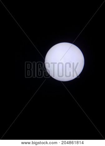 the sun viewed through a solar filter in a telescope with sunspot visible
