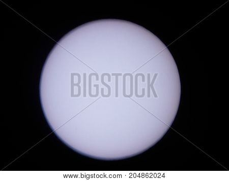 the sun viewed through a solar filter in a telescope with sunspot visible