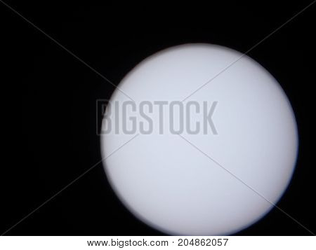 the sun viewed through a solar filter in a telescope with sunspot visible