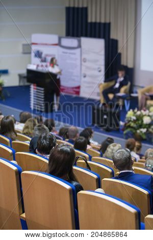 Business Conferences Concepts and Ideas. Group of People Attending Conference and Listening to the Host Speaker. Back View.Vertical Image Orientation