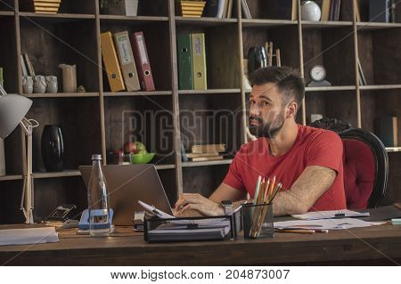 Future plans. Young business man thinking while working with notebook on what next project to do. Creative start up in cozy studio