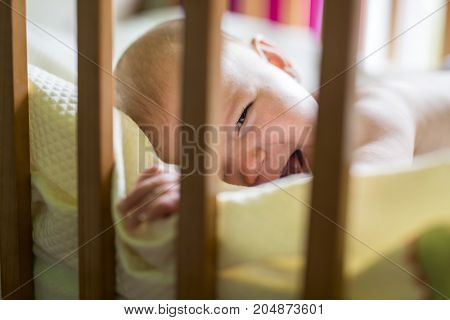 A Close-up portrait of a crying cute baby in the crib at home
