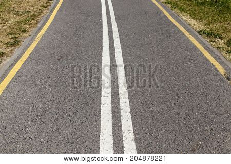 Asphalted Road Divided Into Two Stripes By White Lines. On The Edge Of The Road Yellow Lines