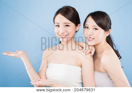two beauty woman show something with healthy skin care on the blue background