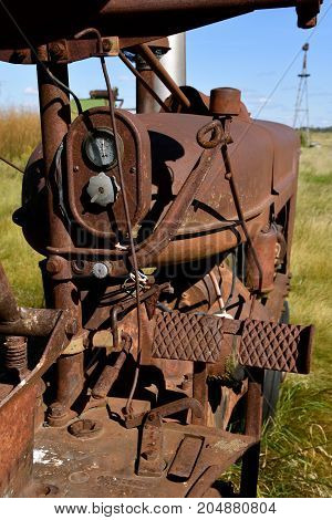 The electric box, gear shift lever, engine mounting,  and foot brake pedals  of an old rusty tractor