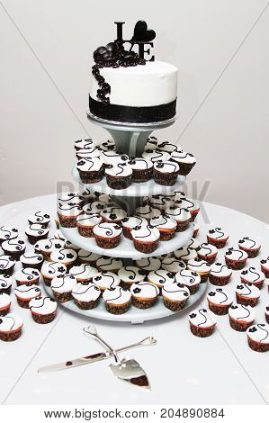 a white and black wedding cake and cupcakes.