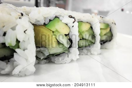 Japanese cuisine. Closeup of fresh veggie maki rolls with avocado.