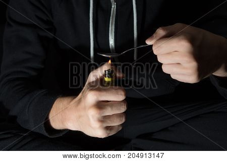 The young man prepares drugs with spoon and lighter