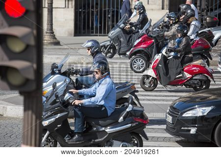 PARIS, FRANCE - June 14, 2013: A few people on scooters are moving through the streets of Paris. Selected focus.