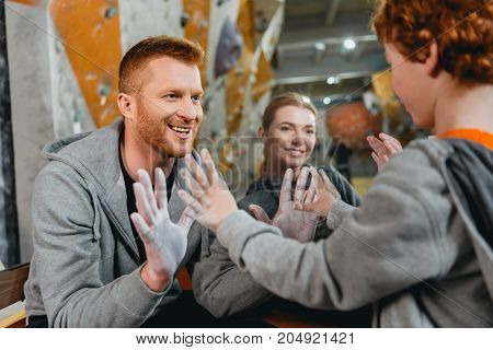 Dad and little son showing each other palms covered in talcum powder and smiling