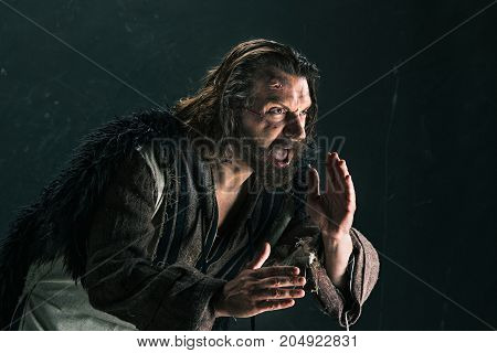 Actor in makeup, a poor man on black studio background. The bum in canvas rags. concept of vagrancy and survival