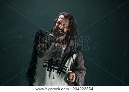 Actor in makeup, a poor man on black studio background. The bum in canvas rags. concept of vagrancy and survival
