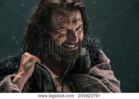 Actor in makeup, a poor man on black studio background. The bum in canvas rags. concept of vagrancy and survival