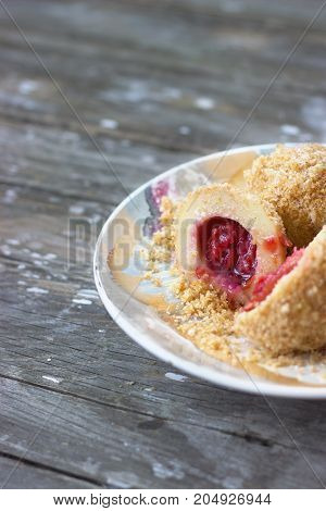 Plum dumplings on colorful plate on wooden background